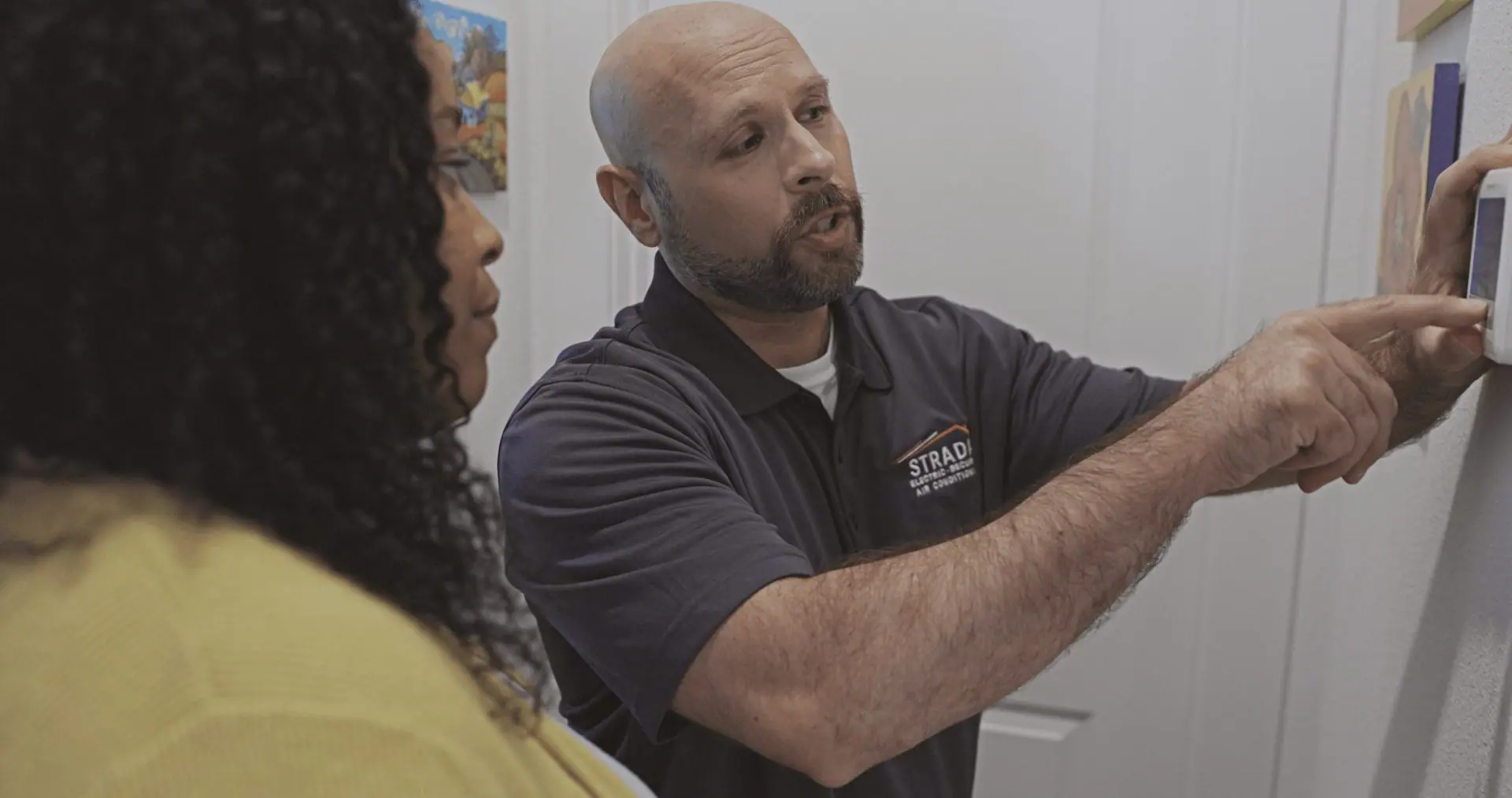 Strada Service technician discussing thermostat to homeowners